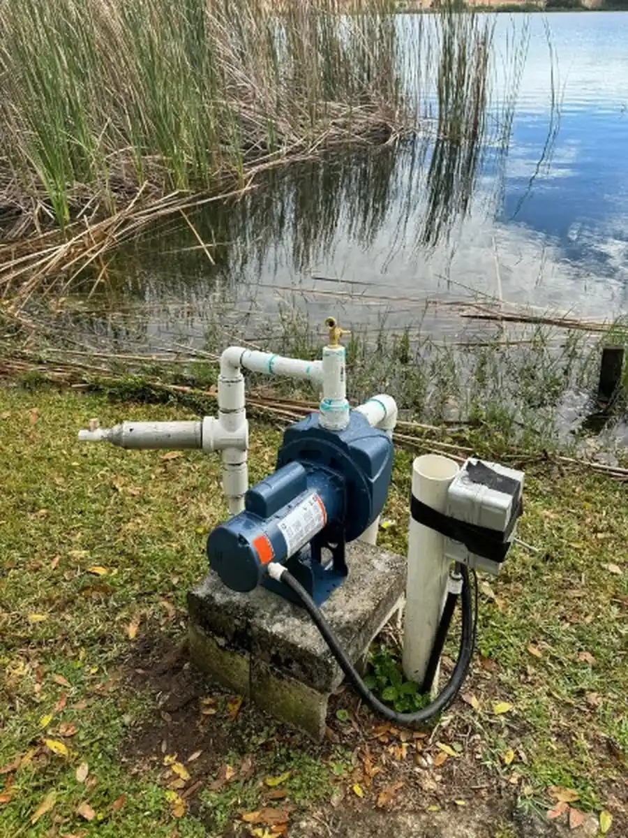 New blue housed irrigation pump with fresh PVC risers on its pad beside a lake in DeLand