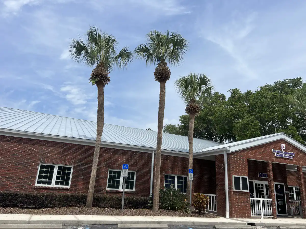 Three freshly trimmed sabal palms standing over the brick clinic building in Osceola County