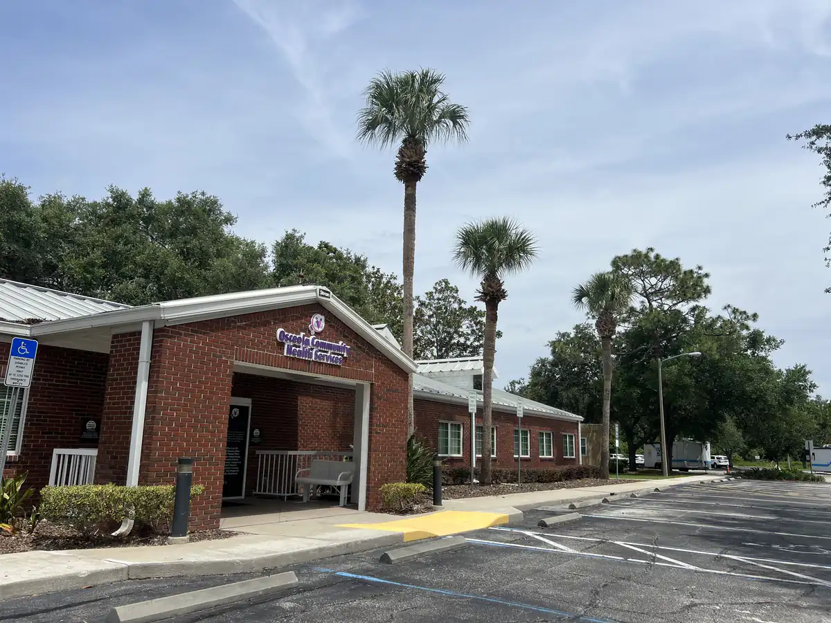 Trimmed palms beside the covered drive through entrance and accessible parking at the Osceola County clinic